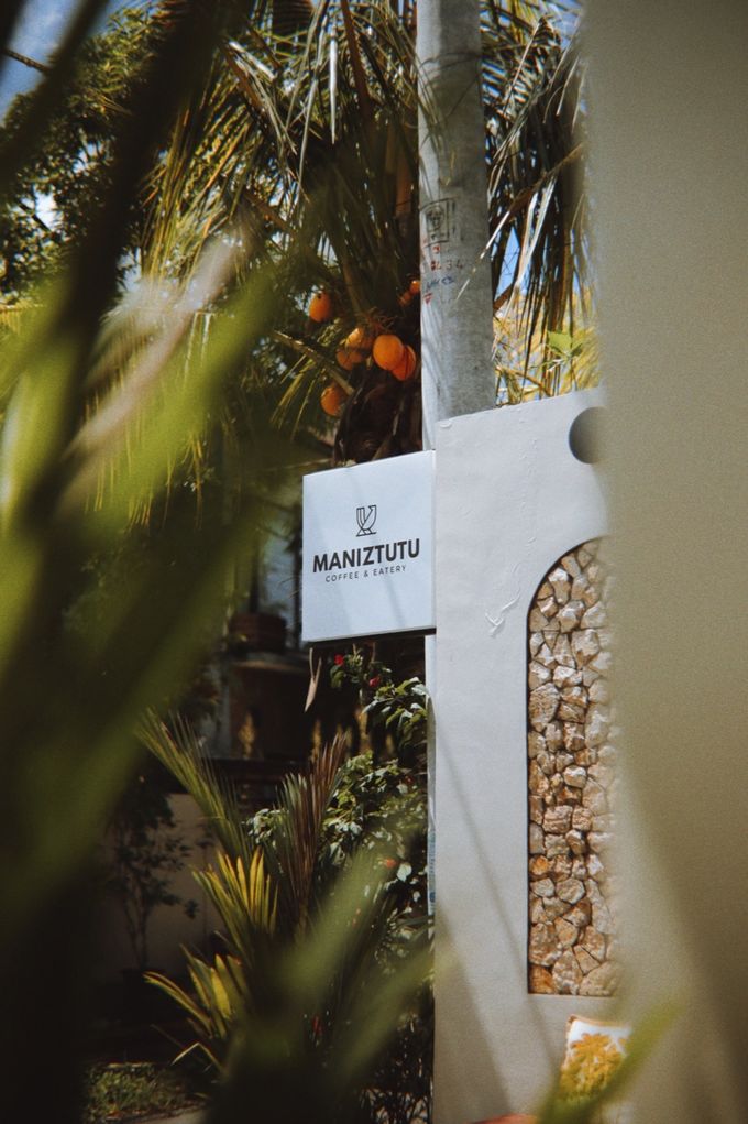 Maniztutu café sign among tropical plants at the entrance