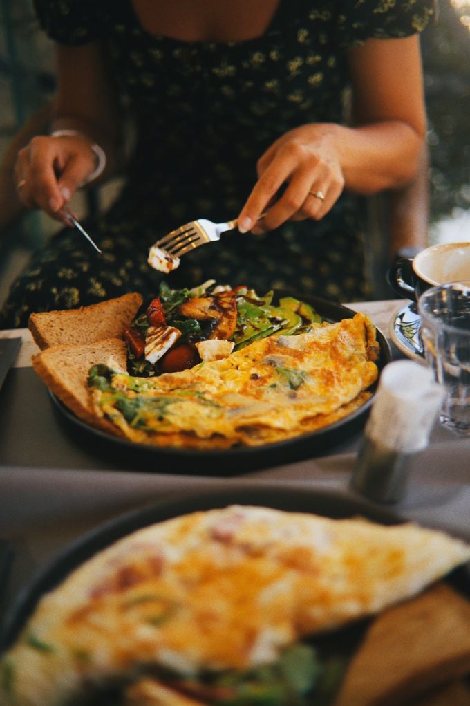 Diner cutting into an omelette with toast and salad