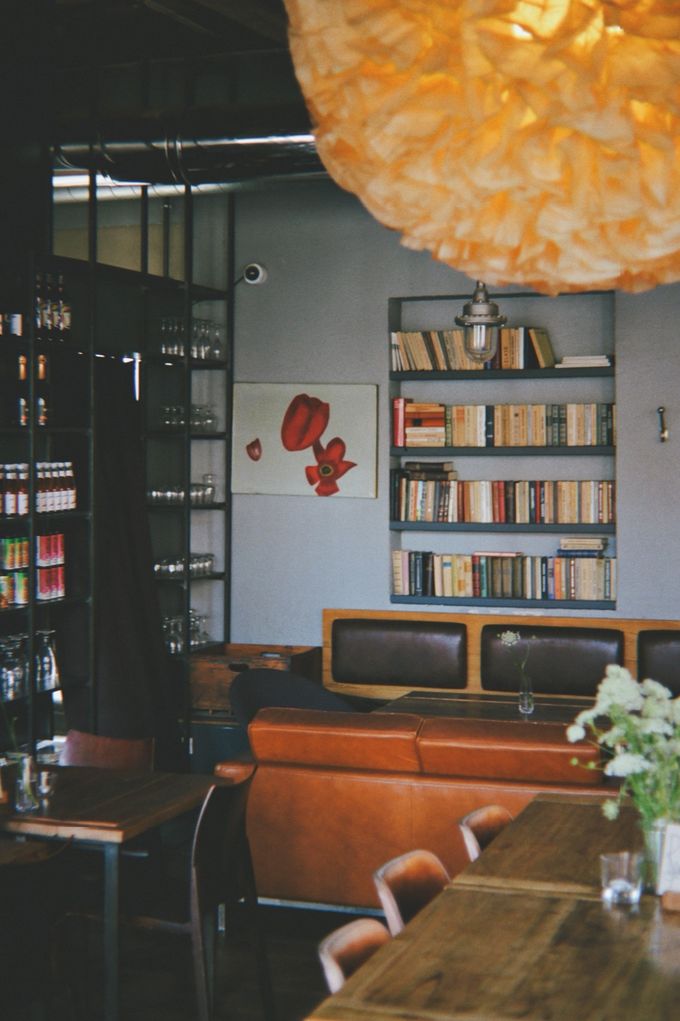 Café interior with a glowing paper pendant lamp, bookshelves and a leather banquette