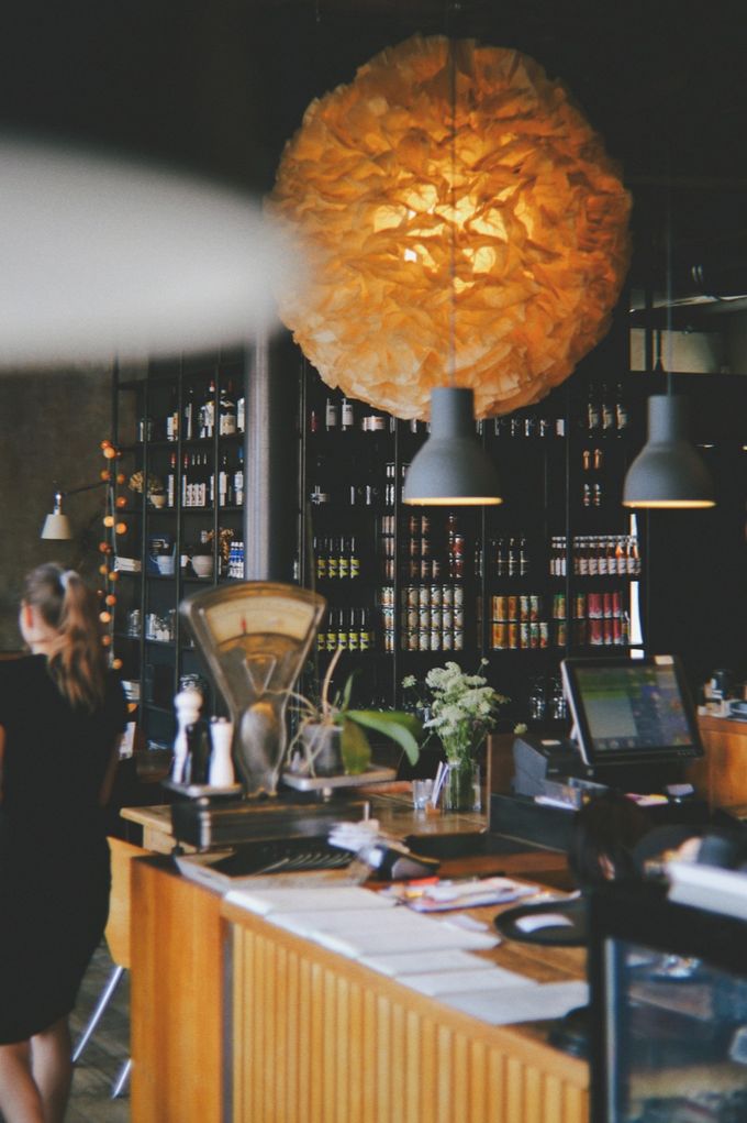 Café counter with a vintage scale and bottle shelves under a paper pendant lamp