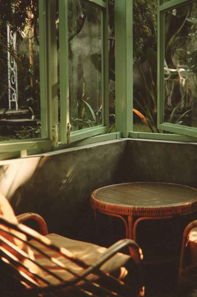 Rattan armchair and table in a green-framed conservatory