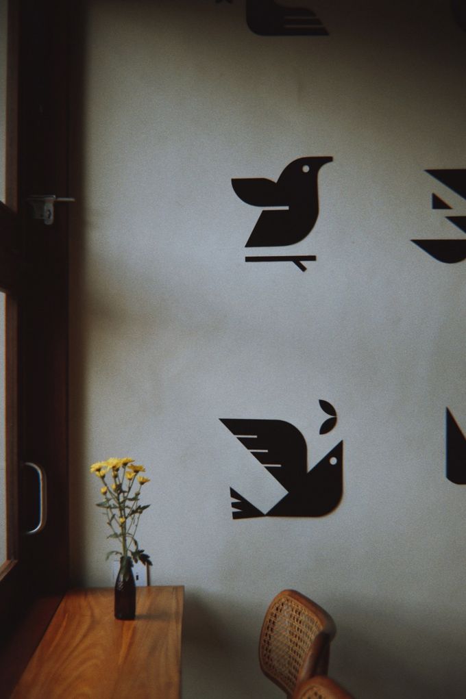 Wall painted with black birds above a small table with yellow flowers