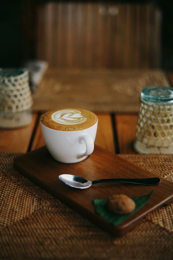 Cappuccino with latte art on a wooden board with a biscuit
