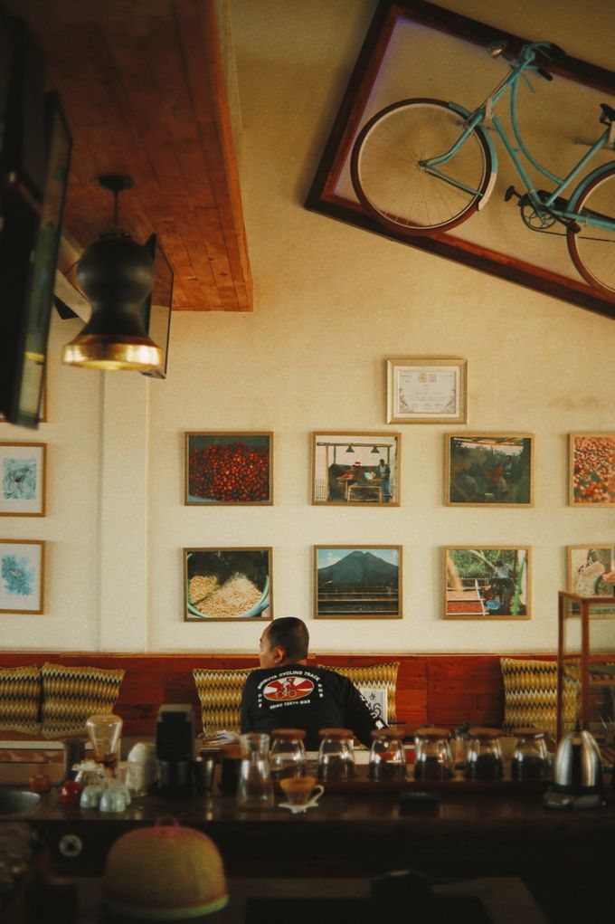 Café wall with a bicycle and framed pictures above the counter