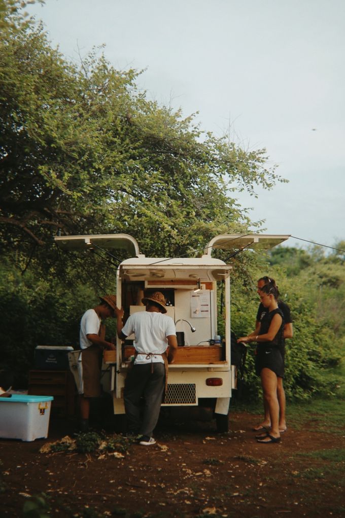 Customers ordering from a coffee truck under the trees