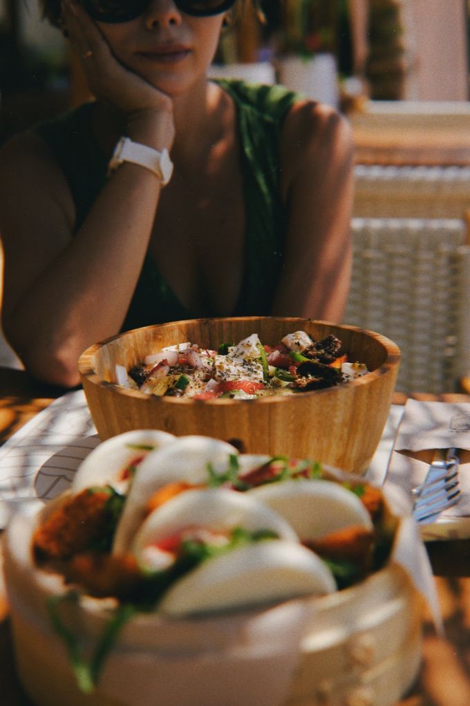 Woman at a table with bao buns and a poke bowl