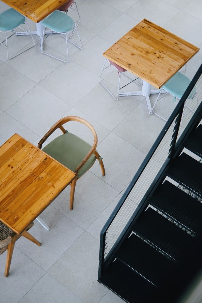 Wooden café tables and chairs seen from the staircase above
