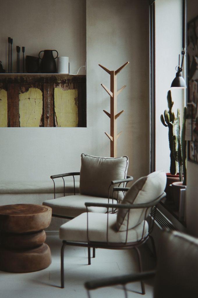 Armchairs, a wooden side table and a coat stand in a bright lounge