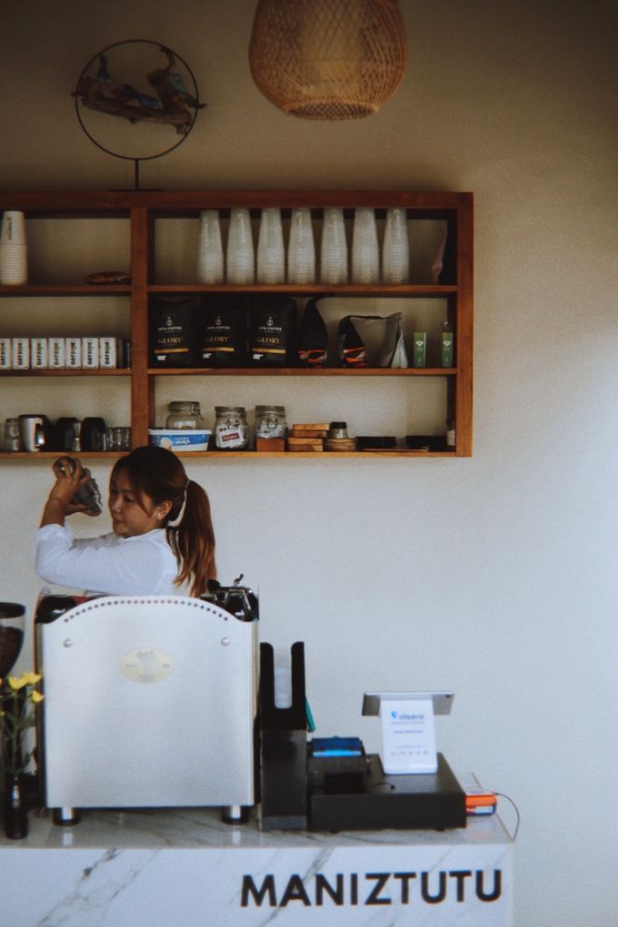 Barista behind a white espresso machine at the Maniztutu counter