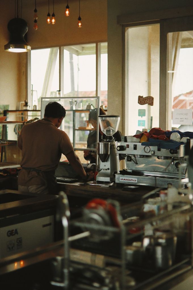 Barista at the espresso machine behind a busy café bar
